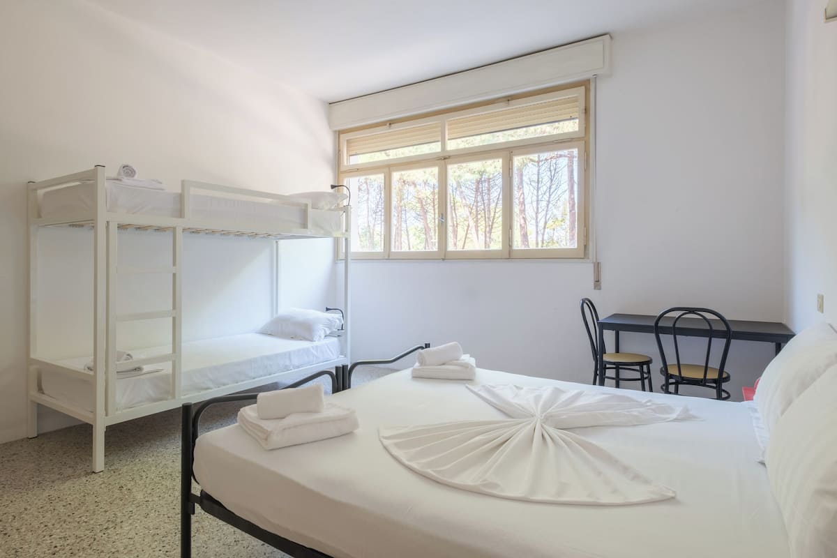 A room with bunk beds, a desk, and a chair.