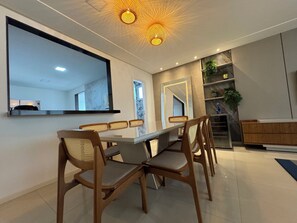 Uma sala de jantar moderna com uma mesa comprida, cadeiras de madeira e um espelho grande.