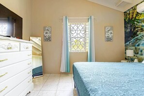 A bedroom with a bed, a dresser, a window with curtains, and wall art. - Private 1BR Near Dunn’s River & Ocho Rios (St. Ann's Bay)