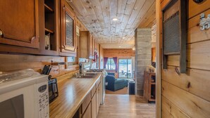 A wooden interior with a kitchen area, including a microwave, stove, and cabinets.