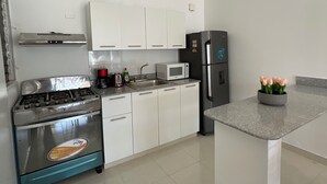 Eine moderne Küche mit weißen Schränken, einem Edelstahl-Kühlschrank, einer Mikrowelle, einem Gasherd und einer Spüle.