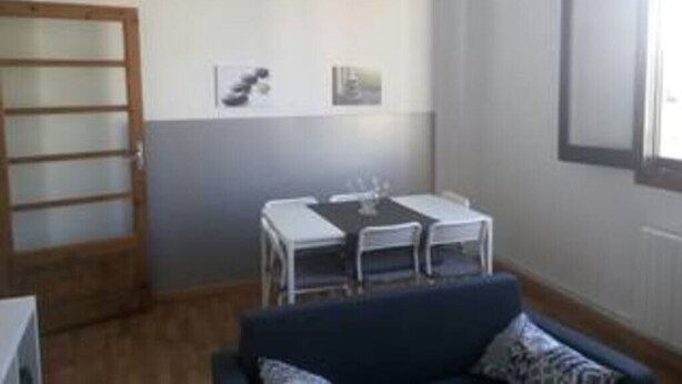 A small room with a dining table and chairs, a sofa, and a ceiling light.