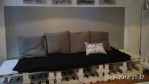 A room with a bed, a bedside table, and a wall with four posters.