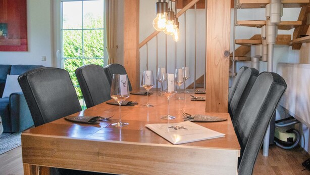 A dining table set with wine glasses and plates, surrounded by chairs. - Ferienhaus in Foetschach (Leutschach an der Weins)