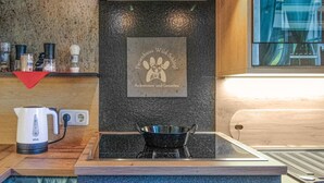 A kitchen with a black countertop, a kettle, a stove, and a wall-mounted sign. - Ferienhaus in Foetschach (Leutschach an der Weins)