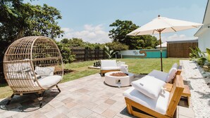 A patio with wicker chairs, a round seating area, and a wooden bench. - 30A Oasis with Lake, Beach, Patio, Fenced Yard for Pets (Panama City Beach)