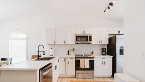 A modern kitchen with white cabinets, a stainless steel oven, a microwave, and a dishwasher. - 30A Oasis with Lake, Beach, Patio, Fenced Yard for Pets (Panama City Beach)