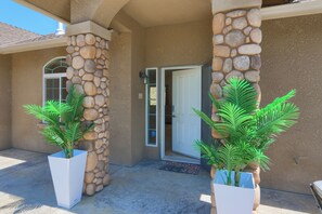 A building entrance with a stone pillar, a door, and two potted plants. - Gated Villa Near Bass Lake, Oakhurst, Mariposa, Yosemite with HotTub, EV Charger (Ahwahnee)
