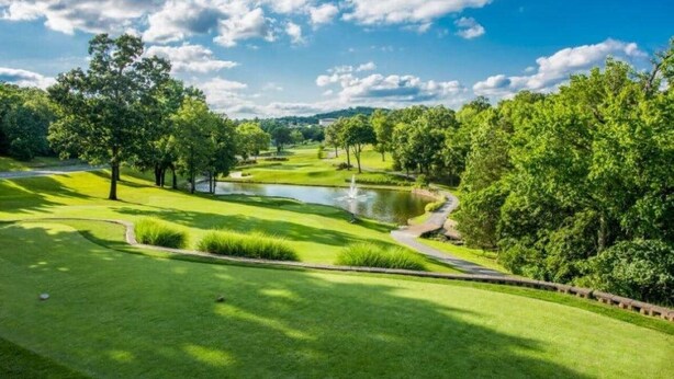 A golf course with a pond, trees, and a clear sky. - The Capital Indoor Outdoor Pool, Hot tub & More (Branson)