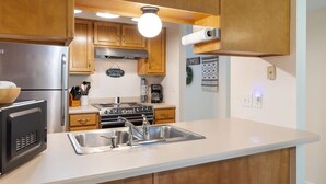 A kitchen with wooden cabinets, a stainless steel refrigerator, a stove, and a sink. - The Capital Indoor Outdoor Pool, Hot tub & More (Branson)