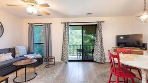 A modern living room with a sofa, coffee table, TV, and dining area with chairs. - The Capital Indoor Outdoor Pool, Hot tub & More (Branson)