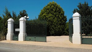 A gated entrance with a large tree in the background. - Όμορφο εξοχικό στούντιο με  πισίνα & κήπο,εύκολη πρόσβαση, 6χλμ από αεροδρόμιο (Kokkini Hani)