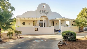 Un bâtiment à l’extérieur blanc, doté d’une entrée en forme de cloche, et sur lequel on peut lire l’inscription « Melted Massage ».