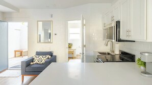 Une cuisine moderne avec des meubles blancs, un évier en acier inoxydable et une cuisinière noire.
