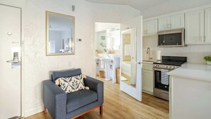 Un appartement moderne avec un canapé gris, une cuisine dotée de meubles blancs, un four à micro-ondes et une cuisinière.