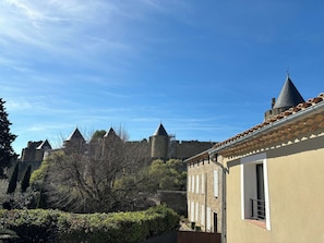 A courtyard with a stone building featuring a tiled roof and a turret. - Gîte La Vade Carcassonne (Carcassonne)