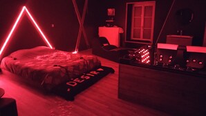 Una habitació poc il·luminada amb un llit, un escriptori i una finestra.