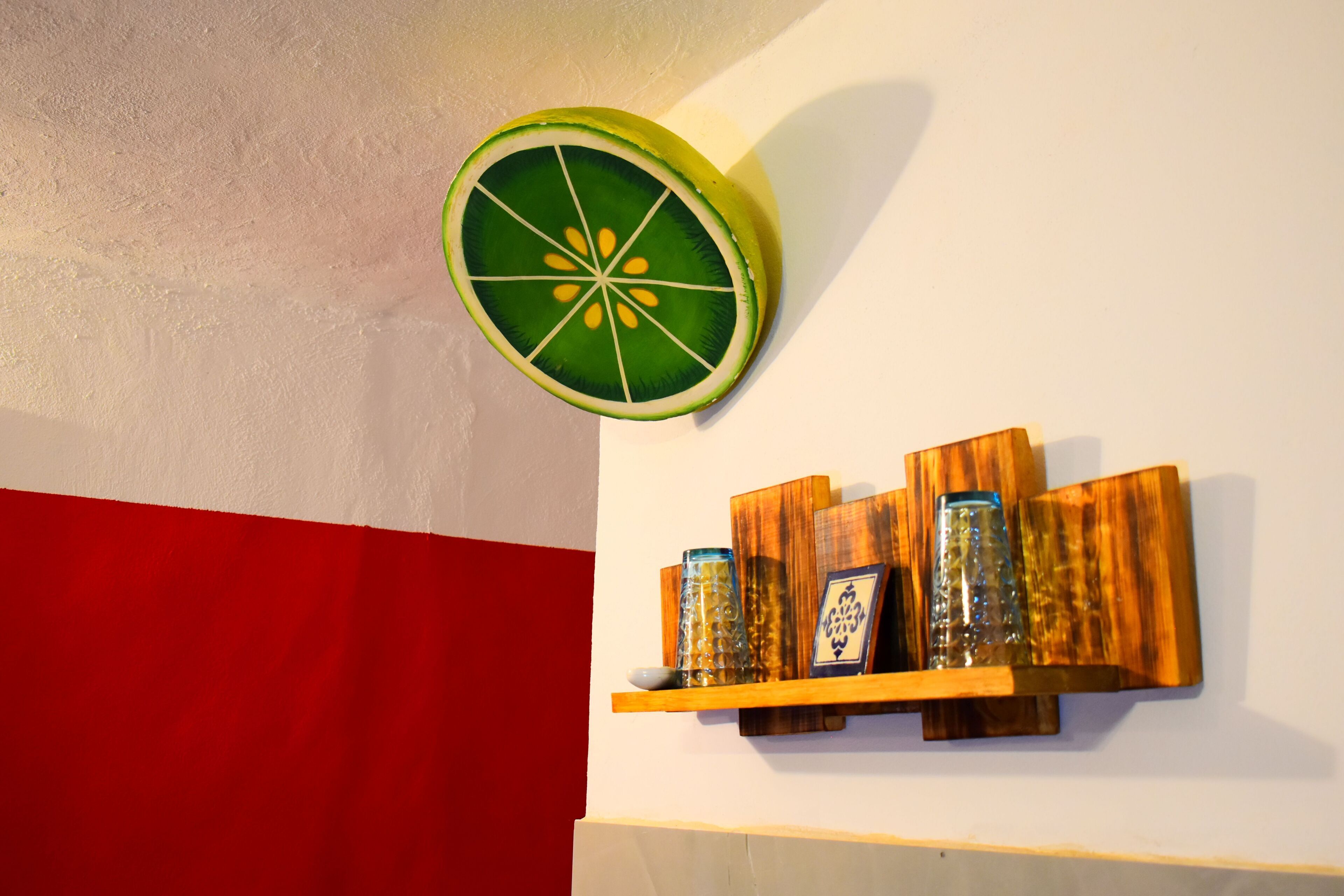Una pared con un estante de madera que sostiene adornos y un reloj de pared.