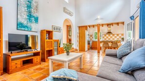 A spacious living room with a television, sofa, and dining area. - Casa Tulipa by dracmallorca (Cala Llombards)