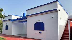 Un bâtiment à l’extérieur blanc, agrémenté de touches de bleu, notamment une porte bleue et des encadrements de fenêtres bleus.