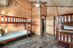 A wooden interior with bunk beds, a ceiling fan, and a door leading to another room. - Free Dollywood Tix/10Min2Dollywood/DogsOK (Sevierville)
