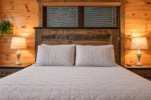 Ein Bett mit Holz Kopfteil, zwei Kissen und Nachttischlampen in einem Zimmer mit Holzwänden.