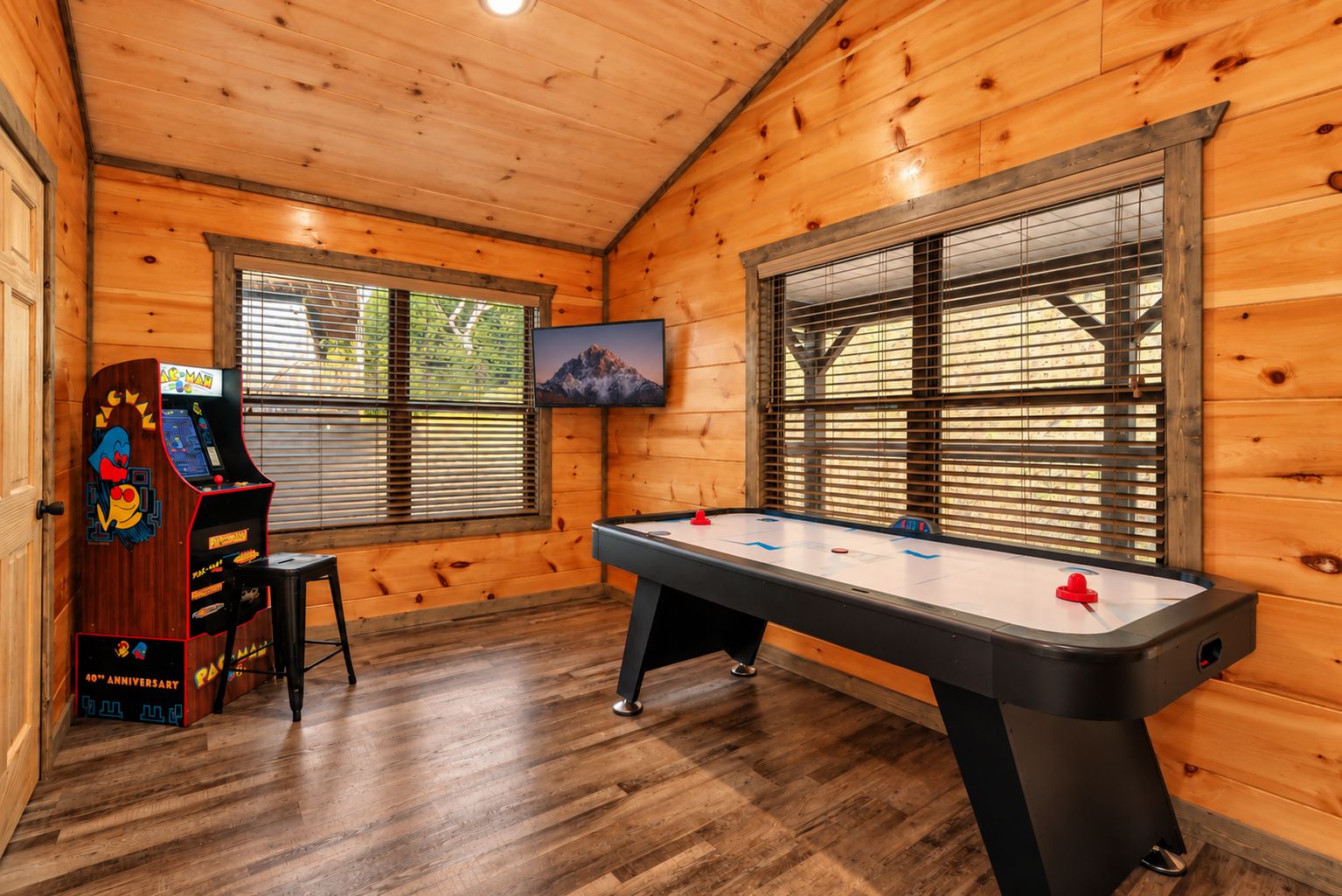 A wooden interior with a pool table, a claw machine, and a television.
