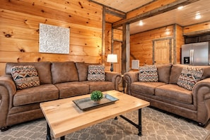 A cozy living room with two brown leather sofas, a wooden coffee table, and patterned cushions.