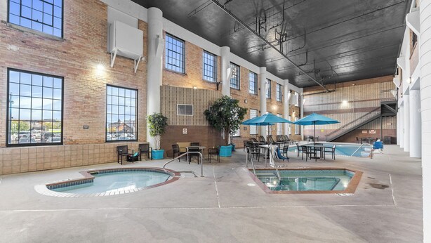 An indoor swimming pool area with multiple pools, seating areas, and a staircase.