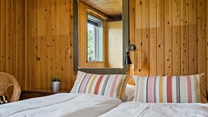 Una habitación de madera con una cama, una planta en maceta y una ventana.