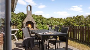 Un patio al aire libre con un horno de pizza de piedra, una mesa y cuatro sillas.