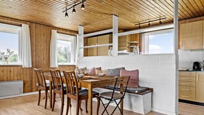 Un comedor acogedor con mobiliario de madera, un banco y una cocina con armarios de madera y una encimera.
