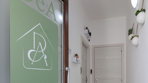A hallway with a green doormat labeled "DeA APARTROOMS" and a door with a similar logo. - DeA ApartRooms (Termoli)