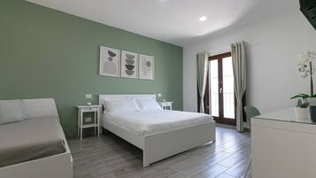 A modern bedroom with a bed, bedside tables, a desk, and a chair.
