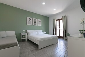 A modern bedroom with a bed, bedside tables, a desk, and a chair. - DeA ApartRooms (Termoli)