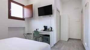A hotel room with a bed, a desk with a computer, a TV mounted on the wall, and a small kitchenette. - DeA ApartRooms (Termoli)
