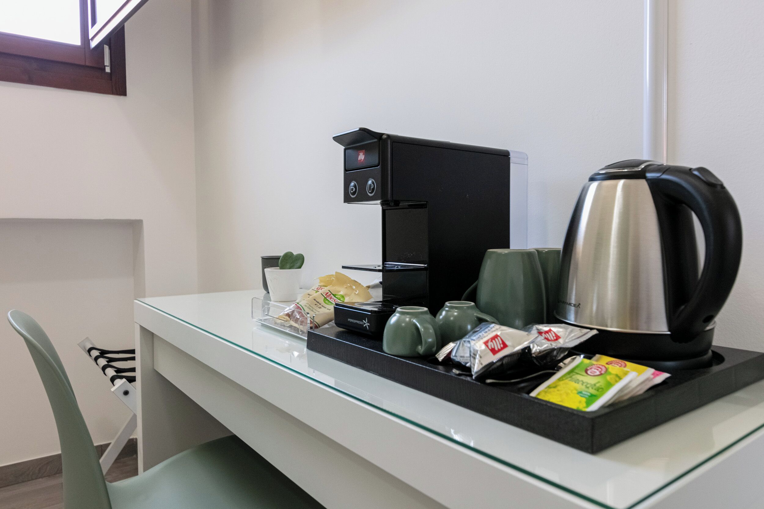 Una cocina moderna con cafetera, hervidor y diversos utensilios de cocina sobre la encimera.