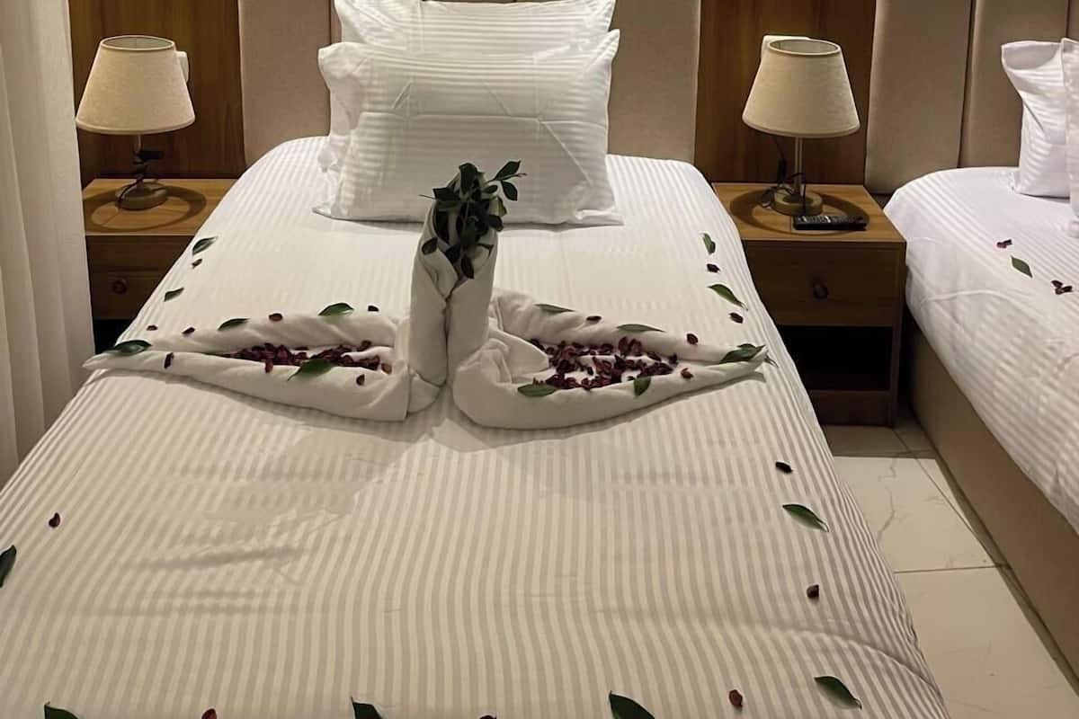 A hotel room with a large bed, two bedside tables with lamps, and a wall with vertical wooden panels.