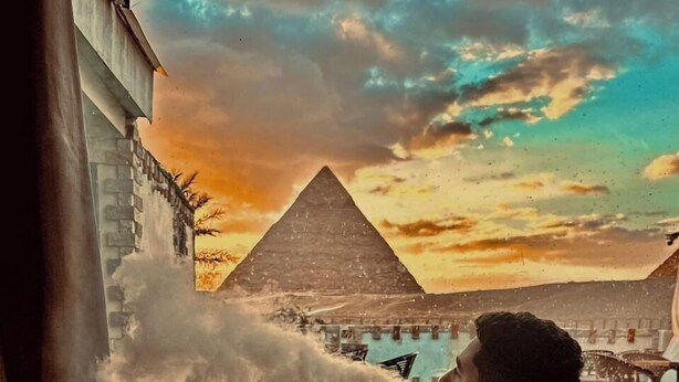 A person relaxing in a large bathtub with a view of a pyramid and a body of water. - White House Pyramids View (Giza)