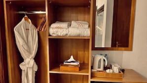 A wooden wardrobe with a mirror, a hanging robe, folded towels, a tissue box, and a small refrigerator. - White House Pyramids View (Giza)