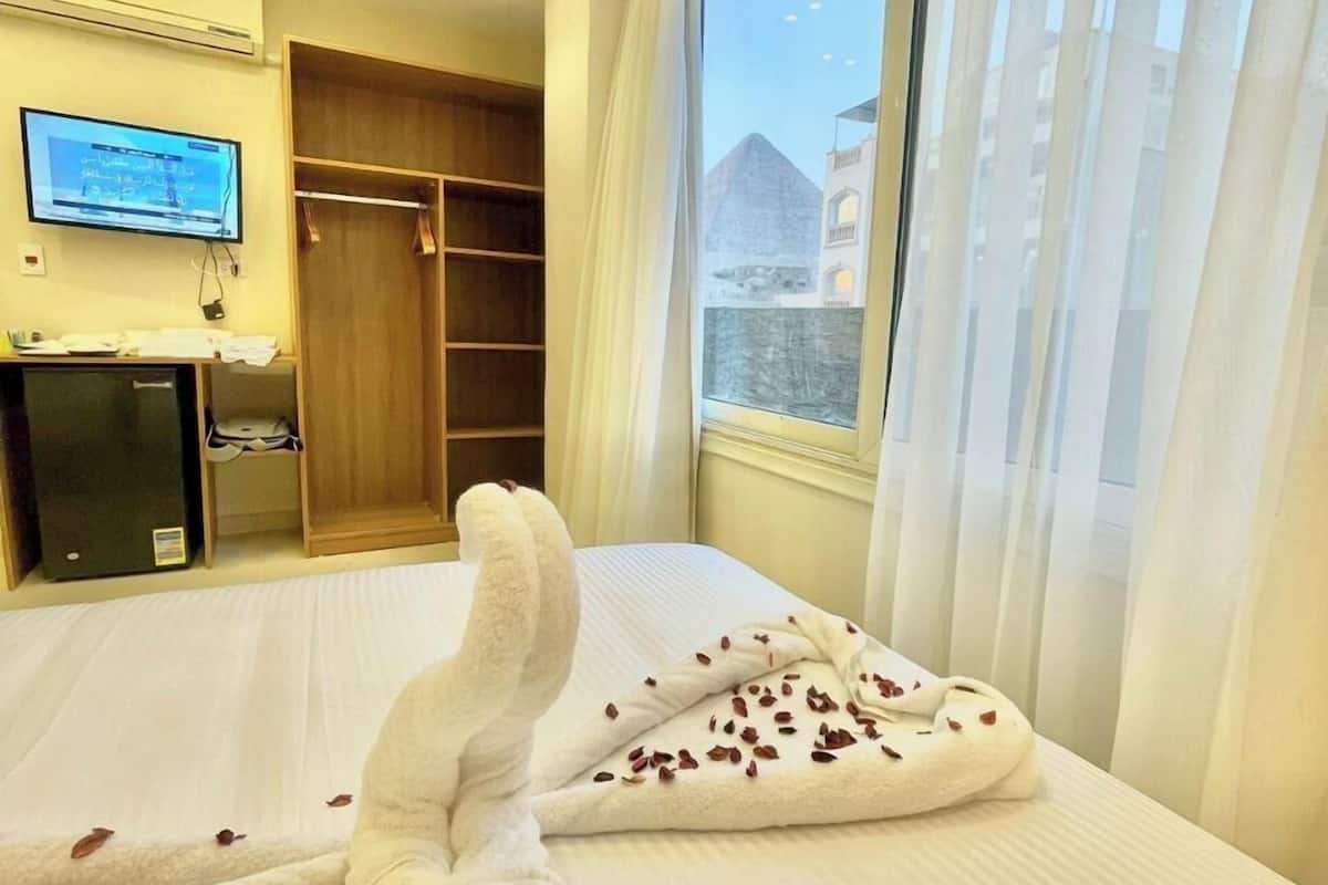 A hotel room with a bed, a TV, a desk, and a wardrobe.