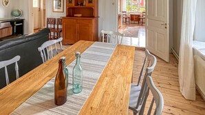 Un comedor con una mesa de madera, sillas y un banco. Hay un aparador de madera con puertas de cristal y un globo terráqueo en un estante.
