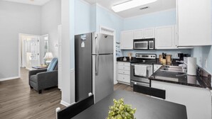 Una cocina moderna con electrodomésticos de acero inoxidable, armarios blancos y una encimera oscura.