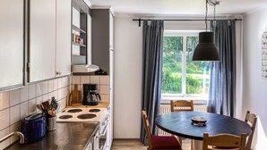 Une cuisine moderne avec des meubles blancs, une cuisinière et un coin repas comprenant une table ronde et des chaises.