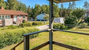 Un quartier résidentiel avec une maison, une allée couverte et un fourgon garé au fond.