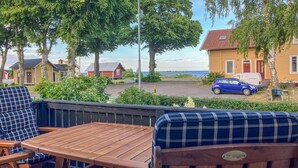 Eine Holterrasse mit Tisch und Stühlen mit Blick auf eine Wohngegend, mit Häusern und einem geparkten Auto.