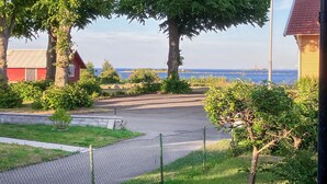 Ein Wohngebiet mit gepflasterter Auffahrt, einem Zaun aus Maschendraht und Blick auf das Meer.