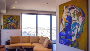Ein modernes Wohnzimmer mit einer gebogenen Couch, einem kleinen Tisch und großen Fenstern mit Blick auf die Stadt.
