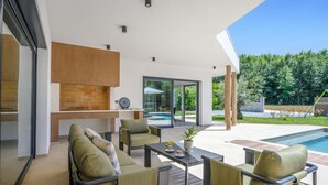Un espace de vie extérieur moderne comprenant une piscine, des sièges et un barbecue.