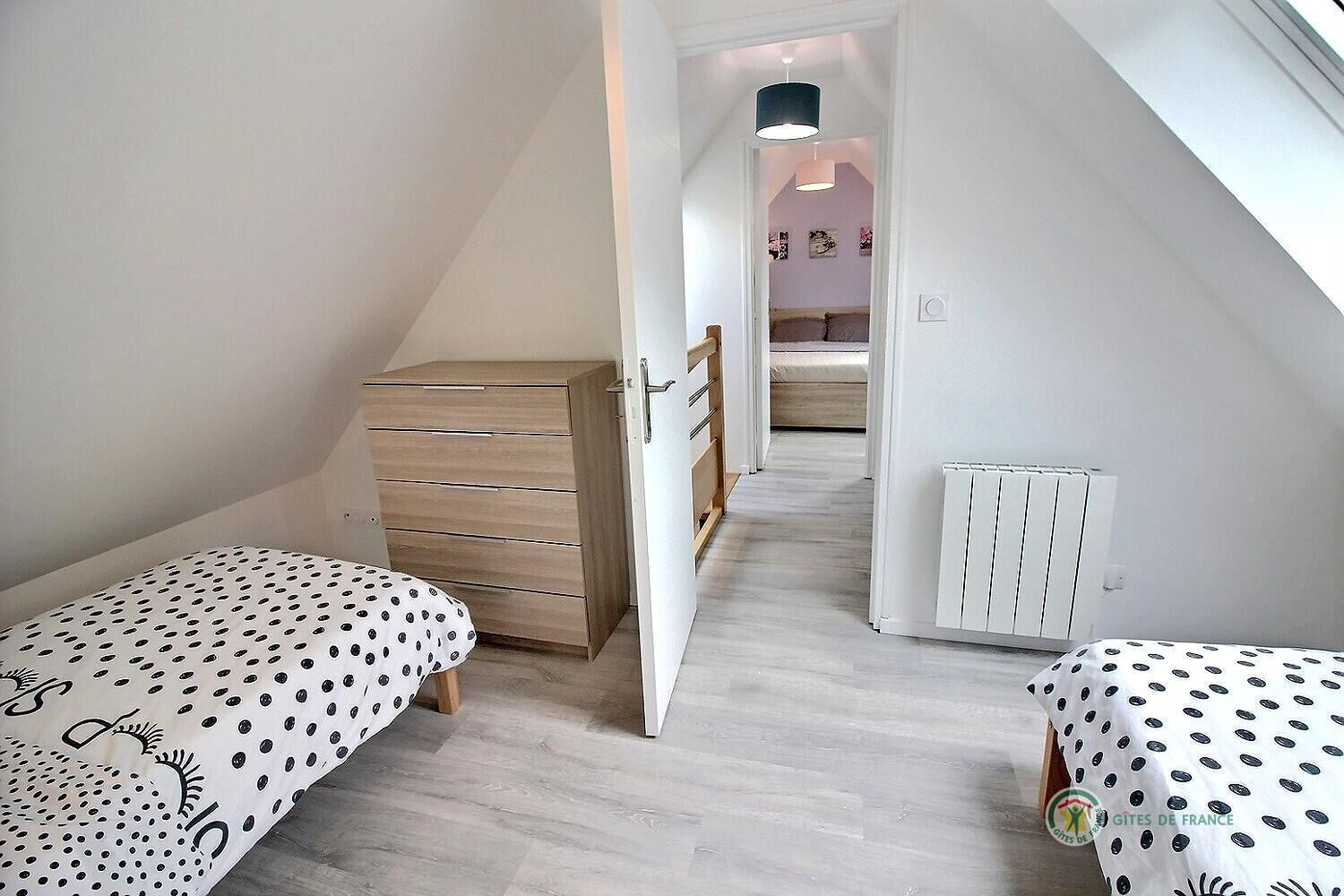 A bedroom with two beds, a wooden dresser, and a radiator.